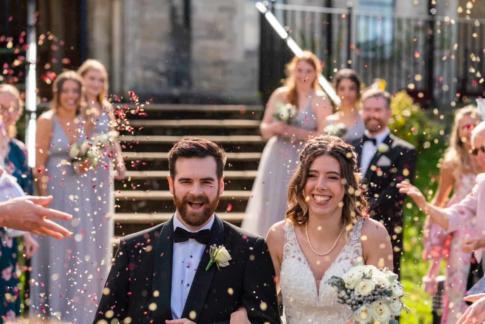 Bride and groom being showered in confetti at their wedding.