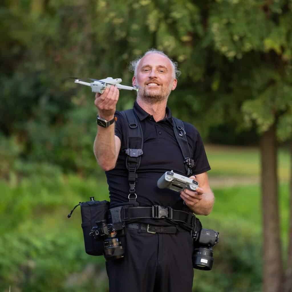 Man with drone and camera equipment outdoors.