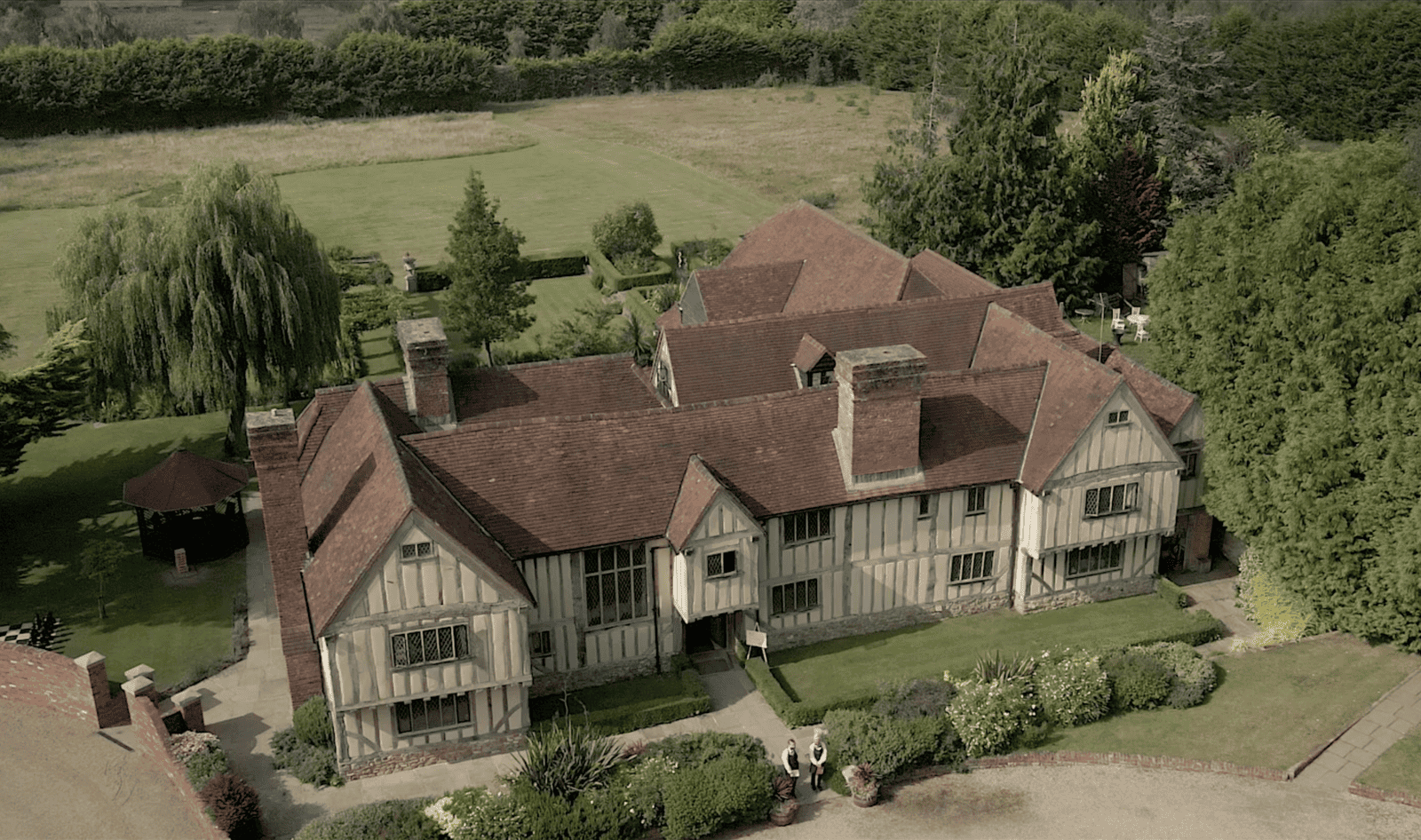 Aerial view of Cain Manor in Hampshire on a wedding day. The front of the property is bathed in soft light, surrounded by lush greenery, creating a romantic and enchanting atmosphere for the celebration