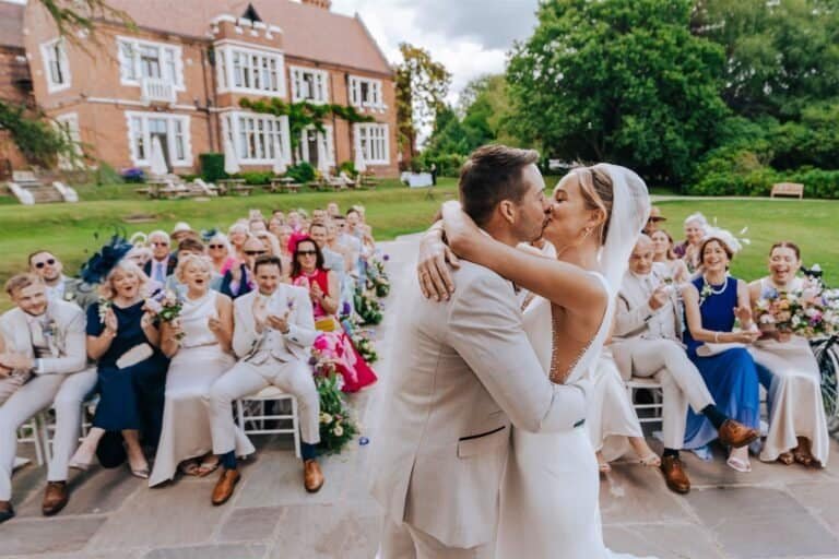 Bride and groom embracing after the outdoor ceremony with seated guests behind them