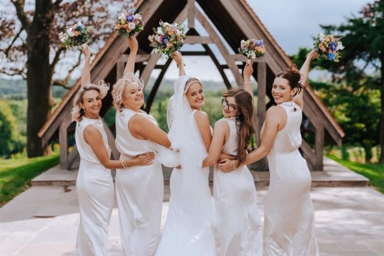Beautiful bridal party celebrating outdoors with wedding bouquets, capturing joyful moments at a rustic venue.