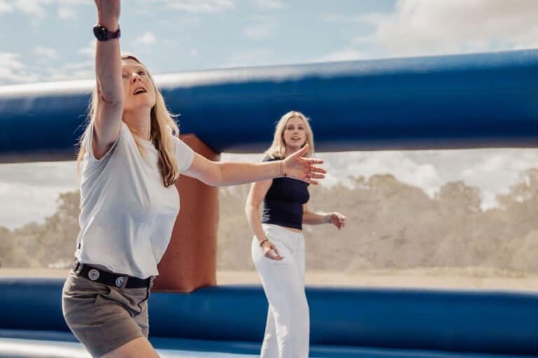 Colleagues playing an inflatable team building game outdoors