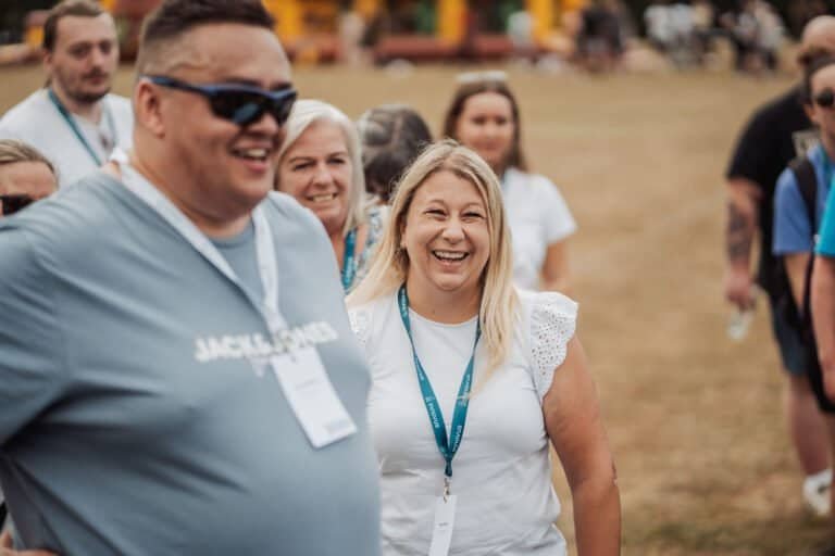 Two colleagues laughing together at an outdoor company event