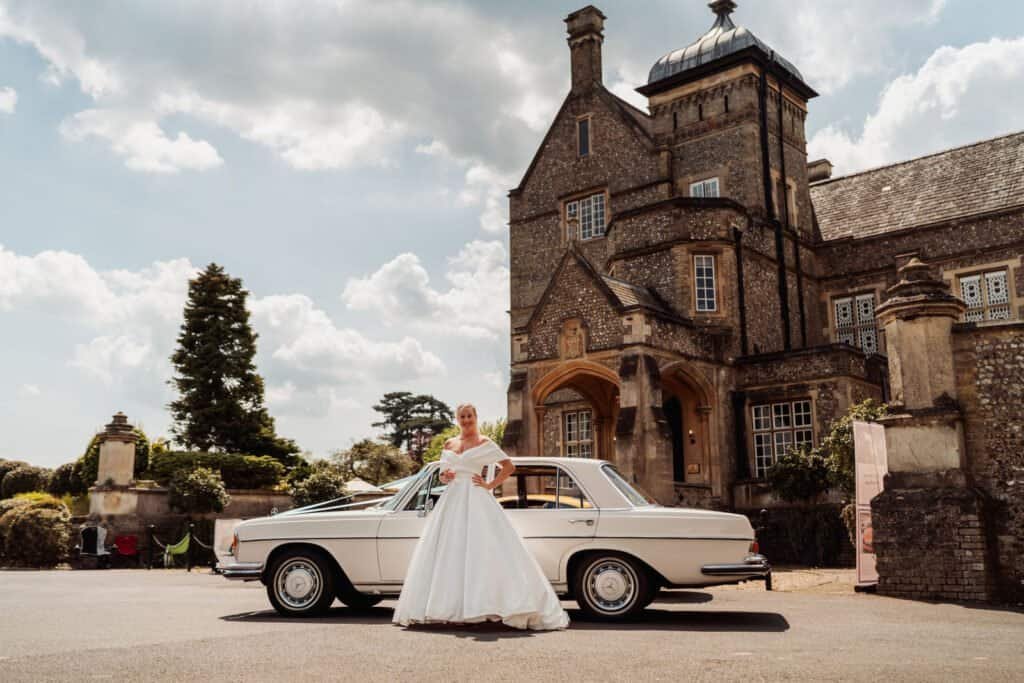 Bride beside a vintage car outside Horsley Towers