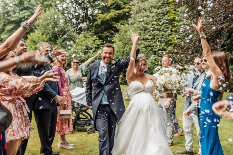 Guests throwing confetti over the newlyweds outside the manor