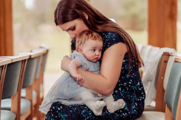 Mother holding her baby quietly during the ceremony