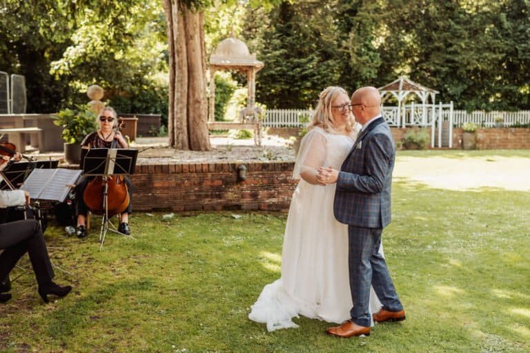 Bride and groom dancing outdoors as a cellist plays