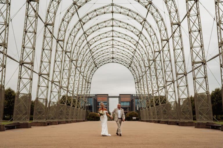 Couple framed at the end of a long steel archway walkway