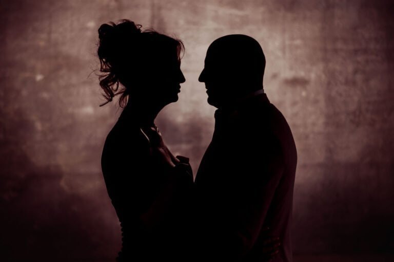 Silhouetted profiles of the bride and groom against warm light