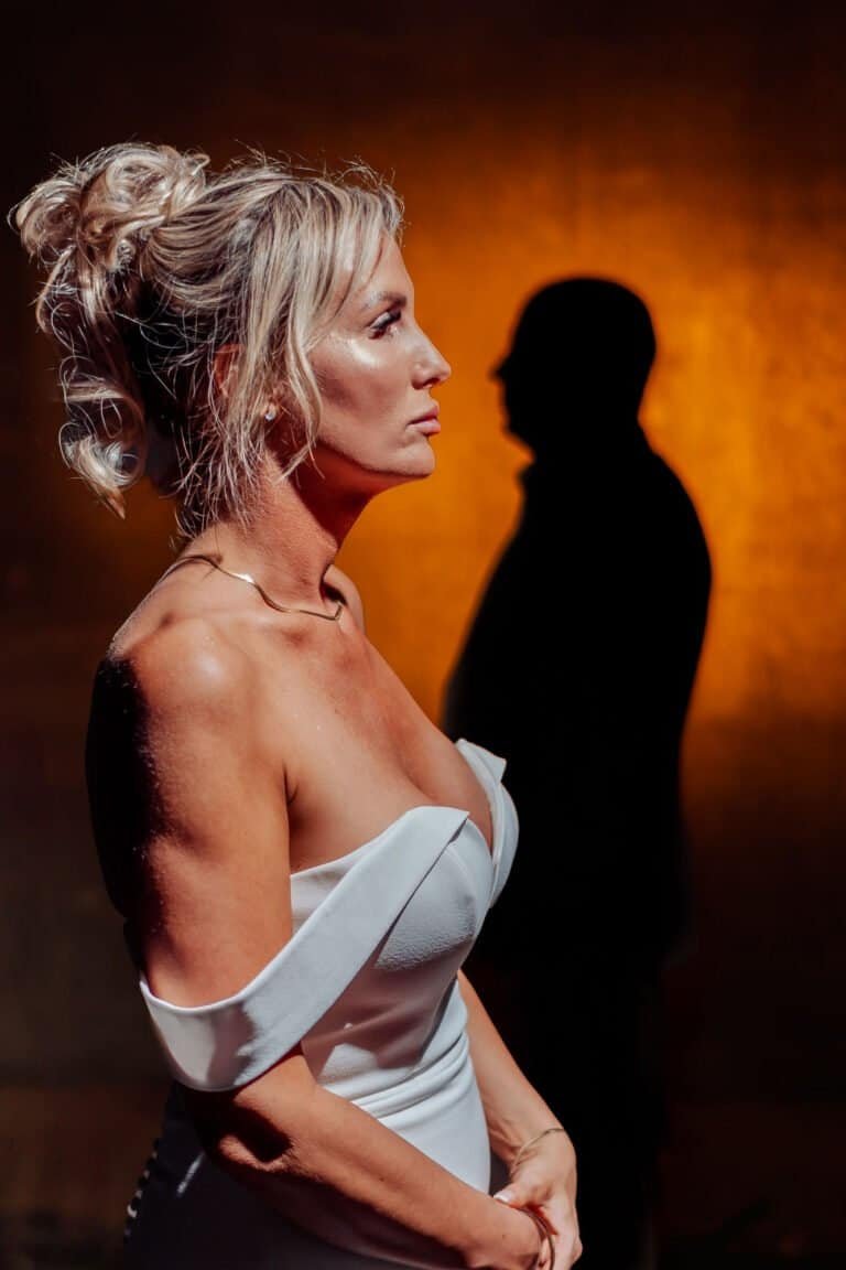 Bride lit against a deep orange wall with the groom in silhouette