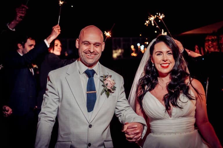 Bride and groom surrounded by sparklers at their winter barn wedding reception