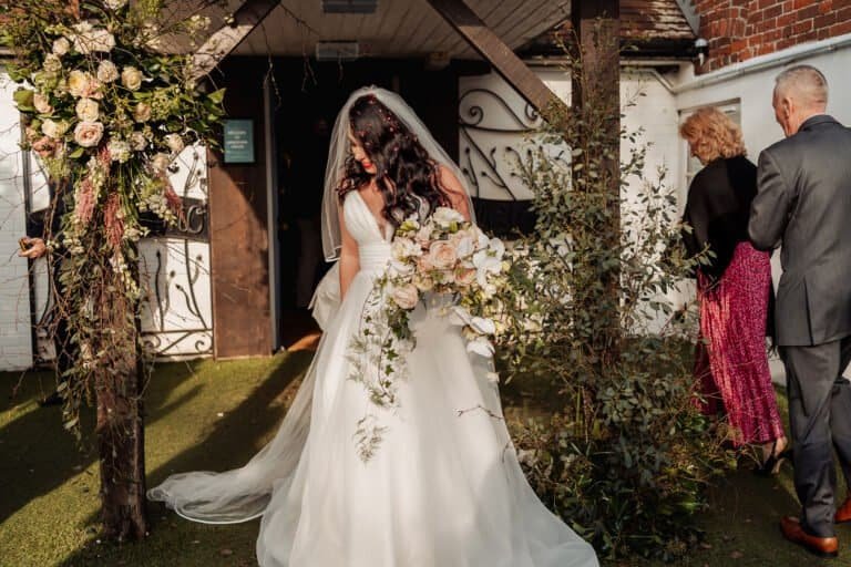 Bride and groom kissing beneath a white floral archway
